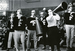Male students in Fairfield sweaters cheer with megaphones at a sporting event