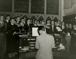 Class of 1951 graduates around church organ